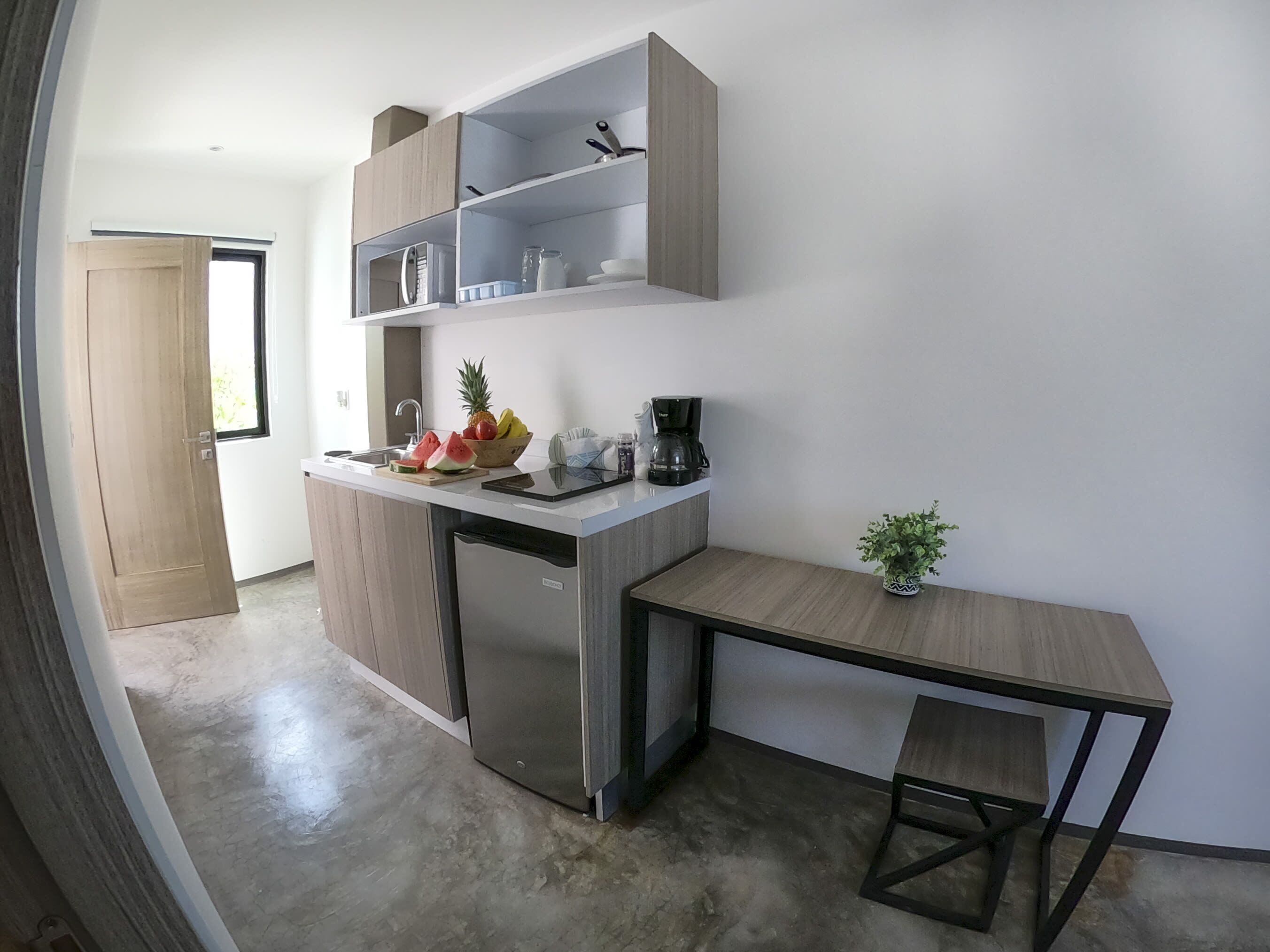 A compact kitchen with a built-in dishwasher, a small dining table, and a potted plant.