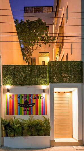 El Mexicano hotel features a modern exterior with a colorful mural and a welcoming entrance.