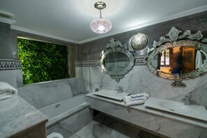 A bathroom with a large mirror, a sink, and a bathtub. There is a green wall and a ceiling light. - Riad Semlalia (Fes)