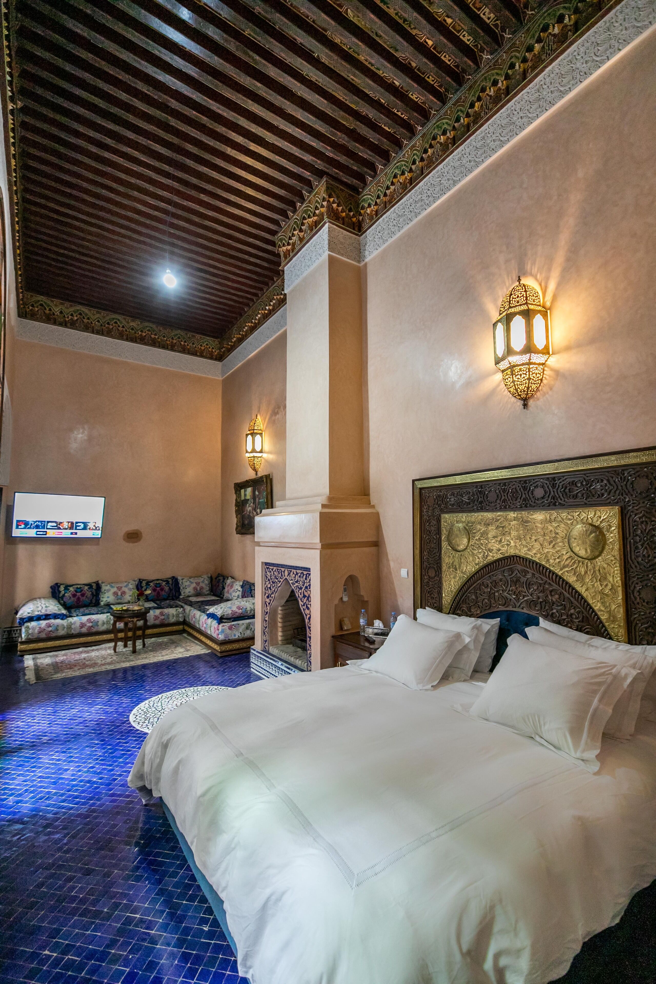 A hotel room with a large bed, a sofa, a small table, and a wall-mounted TV.