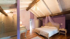 Une chambre avec un plafond en bois, un grand lit à baldaquin, une table de chevet avec une lampe et un espace douche.