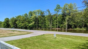 A grassy area with a paved path, a signboard, and a body of water in the background. - Waterfront house on the upper most portion of the West Branch Delaware. (Deposit)