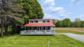 A two-story house with a red roof and a covered porch. - Waterfront house on the upper most portion of the West Branch Delaware. (Deposit)