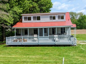 Ein zweistöckiges Haus mit rotem Dach und überdachter Veranda.
