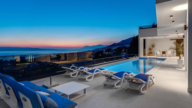 A rooftop pool area with lounge chairs, a table, and a view of the sea and mountains at dusk. - Villa Sagnia, 4 en-suite bedrooms, sea views (Makarska)