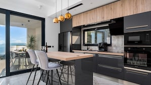 A modern kitchen with a wooden island, black cabinets, and a large window overlooking a scenic view. - Villa Sagnia, 4 en-suite bedrooms, sea views (Makarska)