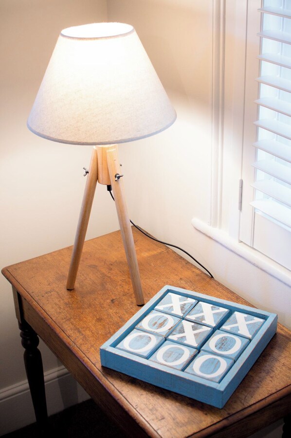 A lamp on a wooden table next to a window with blinds.