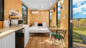 A modern bedroom with a bed, bedside table, and a view of the outdoors.
