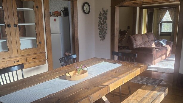 Una mesa de comedor de madera con bancos, un reloj en la pared y decoración rústica.