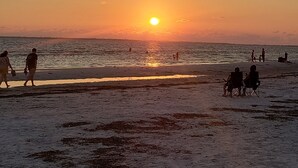 A beach scene at sunset with people walking and sitting on the sand. - Casa Sanibel 3bed 2bth heated Pool home (Fort Myers)