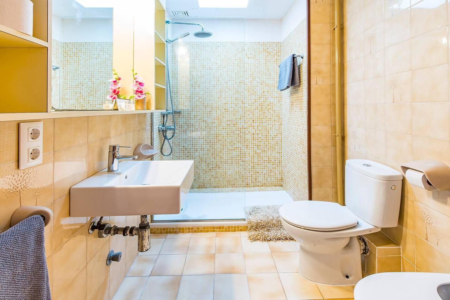 Een moderne badkamer met een douche, toilet, wastafel en een grote spiegel.