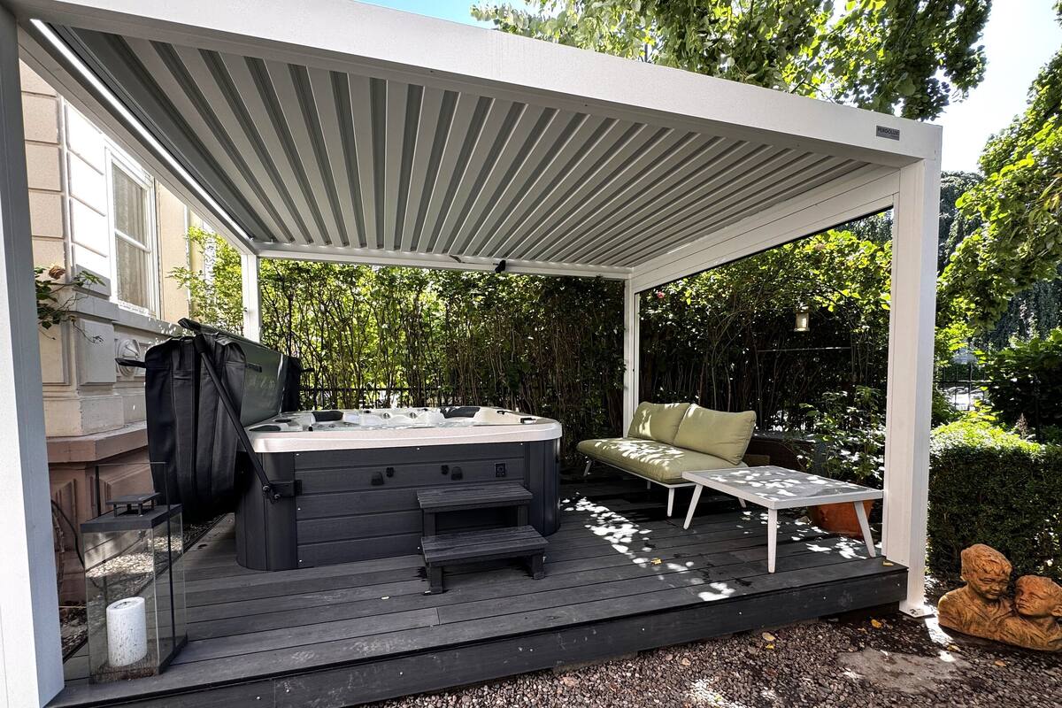 Una terraza cubierta al aire libre con jacuzzi, zona de estar y una parrilla.