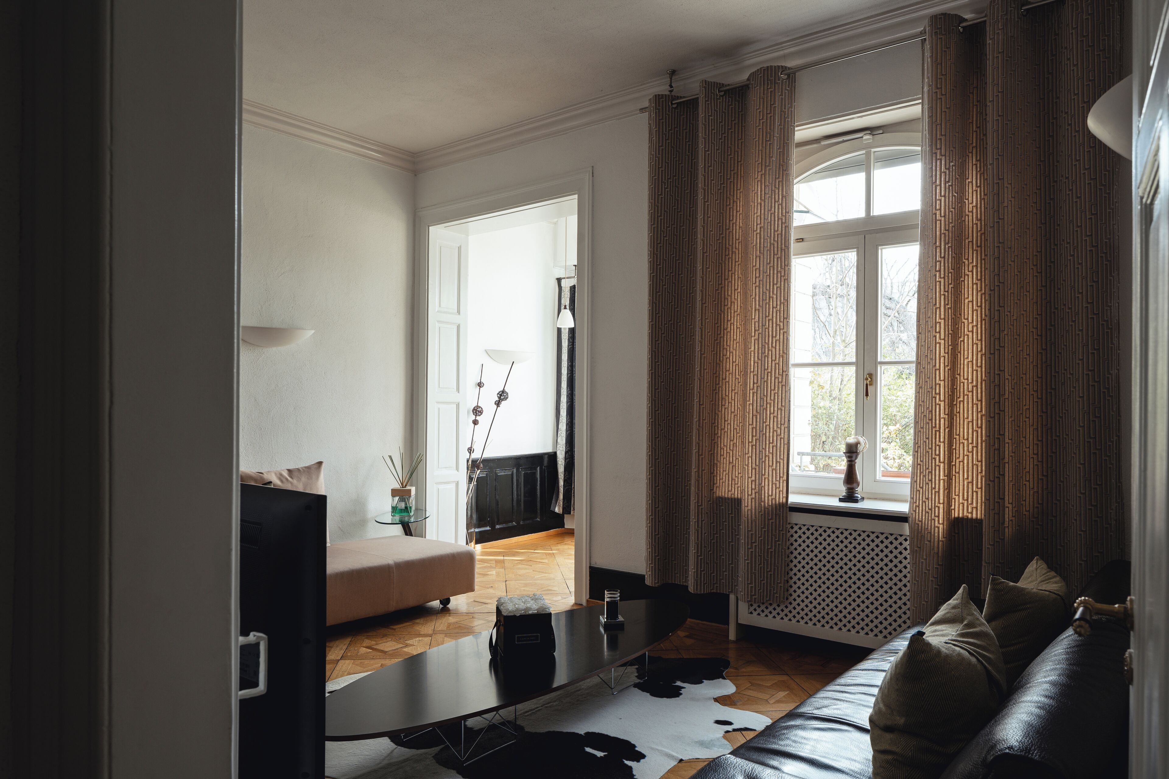 Una sala de estar moderna con un sofá, una mesa de centro y un gran ventanal con cortinas.