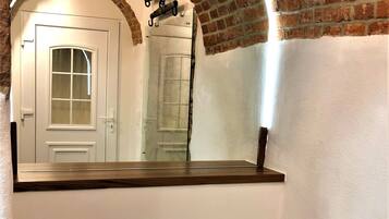 Casa de banho com porta branca, espelho e arco de tijolos.
