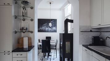 A modern kitchen with a dining area, featuring a black stove, white cabinets, and a black and white tiled floor.