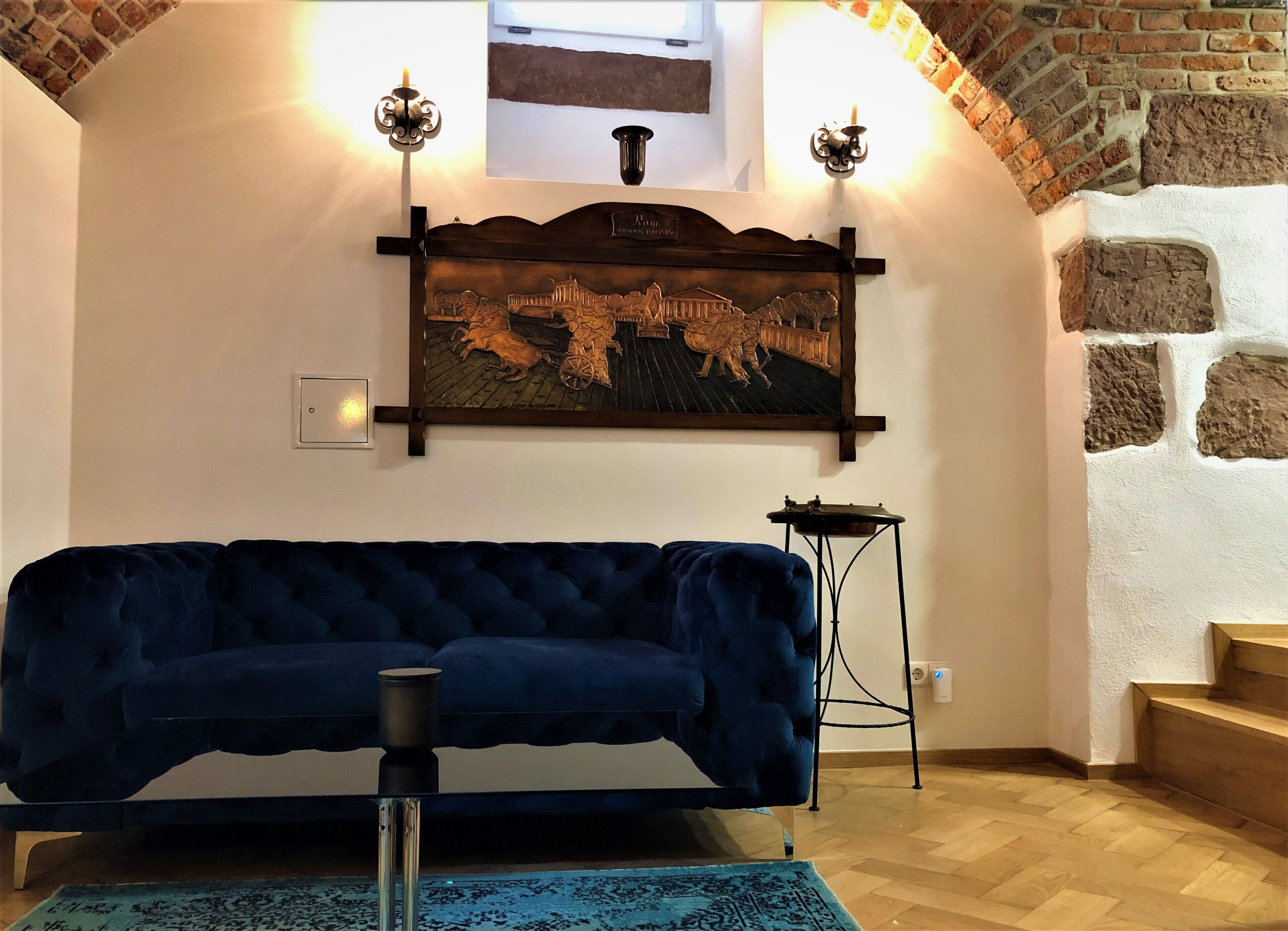 A room with a dark blue sofa, a decorative wall piece, and a small table.
