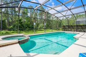 A swimming pool with a glass enclosure, surrounded by a forested area. - Beautiful, Spacious 6 bed Villa on the Gated Watersong Resort (Davenport)