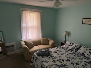 A bedroom with a bed, a chair, a lamp, and a window with curtains. - Historic Beach Side Getaway - Pet Friendly, Wifi 3 Bedroom Cottage by RedAwning (Norfolk)