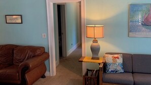 A living room with a brown leather couch, a gray sofa, a wooden coffee table with a lamp, and a painting on the wall. - Historic Beach Side Getaway - Pet Friendly, Wifi 3 Bedroom Cottage by RedAwning (Norfolk)