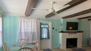 A dining area with a table and chairs, a fireplace, and a ceiling fan. - Historic Beach Side Getaway - Pet Friendly, Wifi 3 Bedroom Cottage by RedAwning (Norfolk)