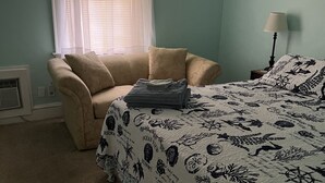 A bedroom with a bed, a chair, a lamp, and a window with curtains. - Historic Beach Side Getaway - Pet Friendly, Wifi 3 Bedroom Cottage by RedAwning (Norfolk)