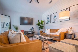 A modern living room with a sofa, coffee table, and wall-mounted TV.