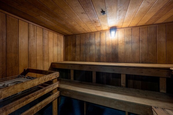 A sauna room with wooden benches and a bench with a metal frame.