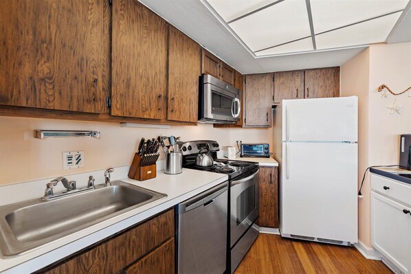 A modern kitchen with wooden cabinets, stainless steel appliances, and a white refrigerator.
