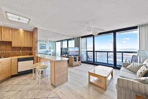 Enjoy ocean views from the large window in this living space, featuring a kitchen area with a flat-screen TV and comfortable seating.