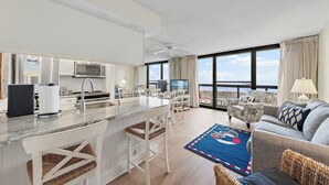 Een moderne keuken met een bar, een eethoek en een zithoek met een bank en televisie.