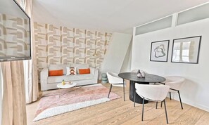 A modern living room with a sofa, a round dining table, and two chairs. - ENCHANTING SAINT-GERMAIN HIDEAWAY:3-BEDROOM HOME STEPS FROM PARISIAN LANDMARKS (Paris)