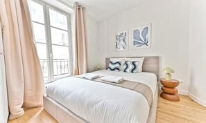 Une chambre moderne avec un grand lit, une table de chevet et une fenêtre avec des rideaux.