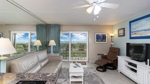 Ein modernes Wohnzimmer mit einer Couch, einem Couchtisch, einem Fernseher und einem Deckenventilator.