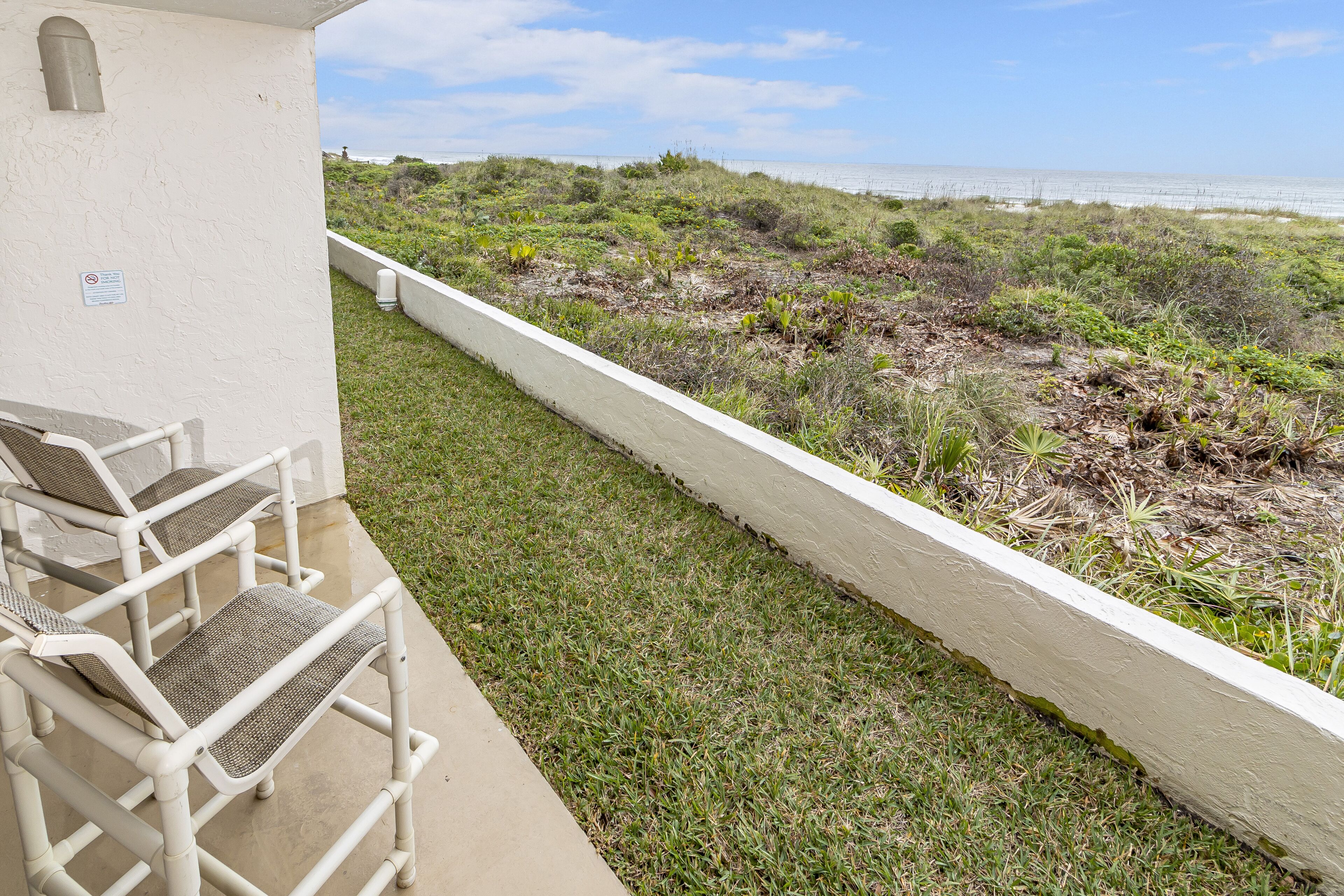 Eine Terrassenfläche mit Gartenmöbeln und Blick auf den Strand.