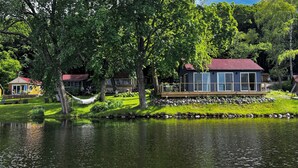 Un chalet au bord du lac, doté d’une terrasse et entouré d’une végétation luxuriante, avec un lac paisible à proximité.