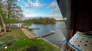 Une vue sur la rivière, avec un quai, une zone herbeuse et des arbres.