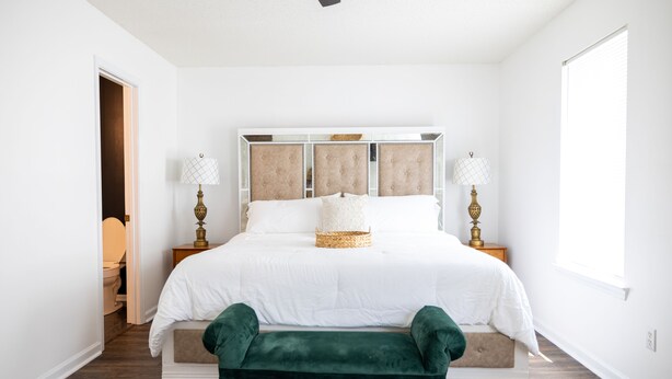 A bedroom with a large bed, bedside lamps, and a bench.