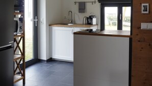 Une cuisine moderne avec un plafond en bois, un four à micro-ondes encastré et un évier.