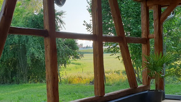 Une terrasse en bois offrant une vue sur un champ verdoyant et des arbres.