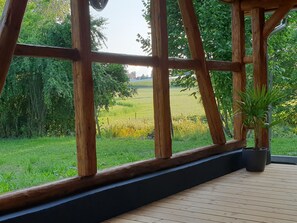 Une terrasse en bois offrant une vue sur un champ verdoyant et des arbres.