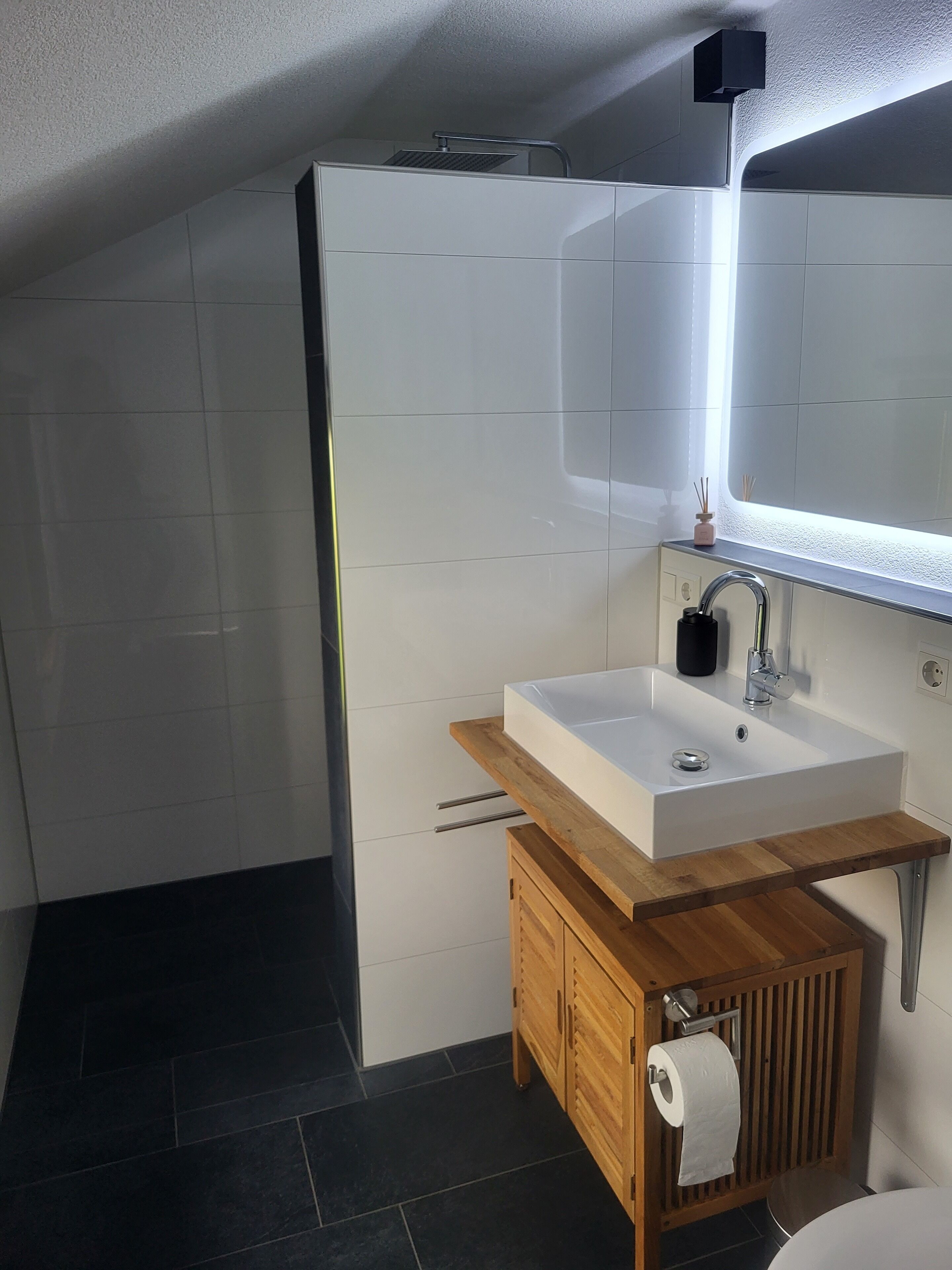 A modern bathroom with a white sink, wooden vanity, and a large mirror above the sink.