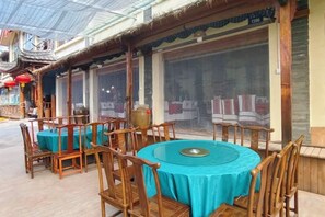 A restaurant with round tables and chairs, a traditional roof, and large windows. - Tiandi Renhe Inn (Shilin)