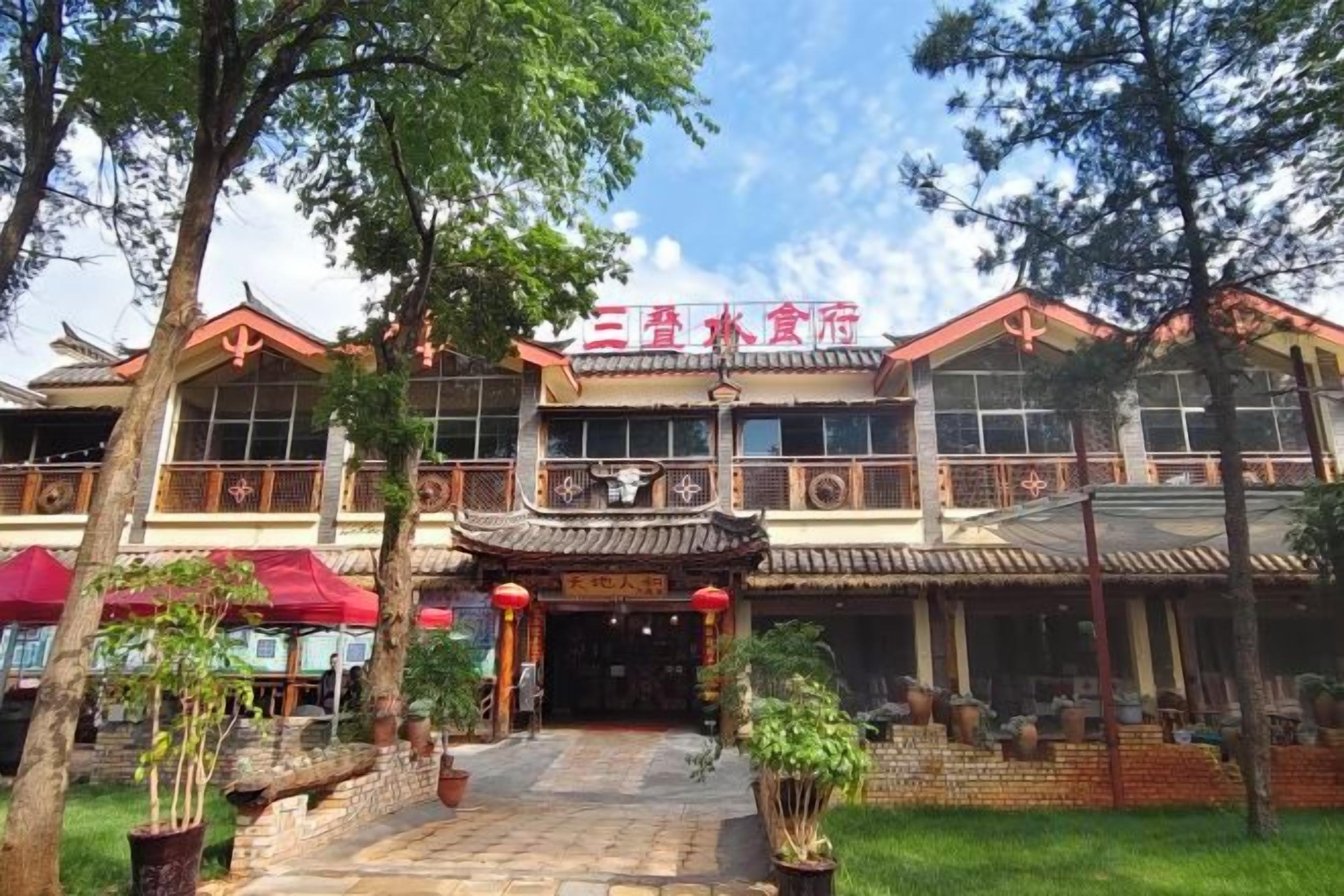 A traditional building with a red sign, a tiled entrance, and a courtyard with potted plants.