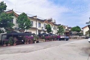 A street with traditional buildings, outdoor seating, and cars parked along the road. - Tiandi Renhe Inn (Shilin)