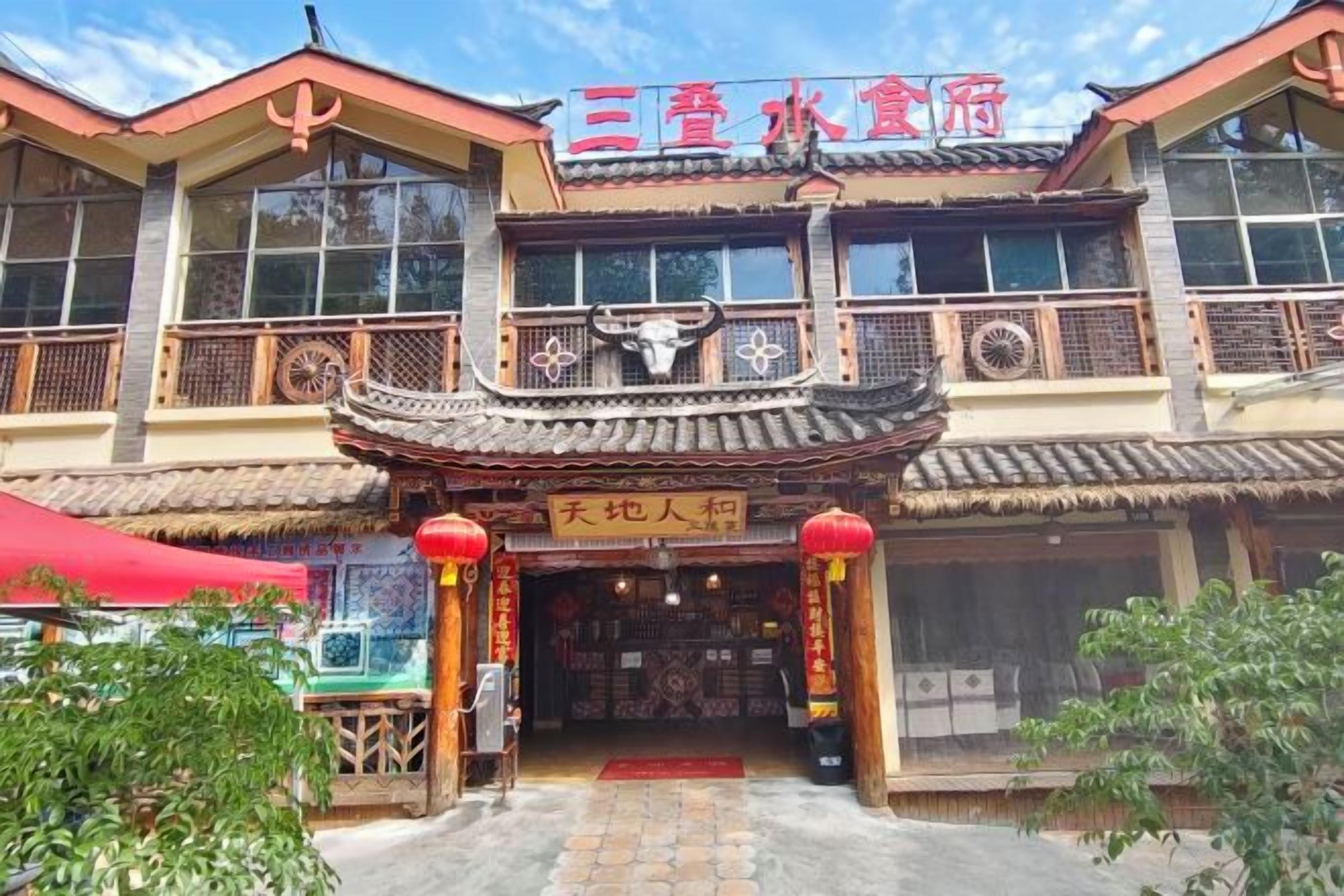 Un edificio tradicional con un letrero que dice '三春水饺店' y una cartelera con caracteres chinos.