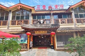 Ein traditionelles Gebäude mit einem Schild, das '三春水饺店' zeigt, und einer Werbetafel mit chinesischen Schriftzeichen.