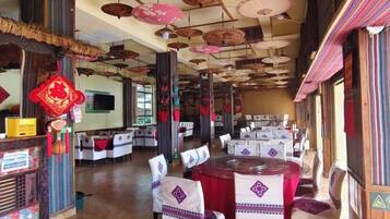A restaurant with tables set for dining, a television screen, and traditional decorations.