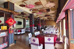 A restaurant with tables set for dining, a television screen, and traditional decorations. - Tiandi Renhe Inn (Shilin)