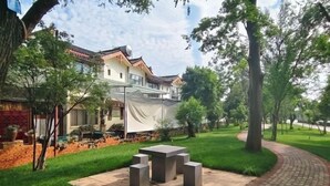 A courtyard with a stone table and benches, surrounded by a brick wall and greenery. - Tiandi Renhe Inn (Shilin)