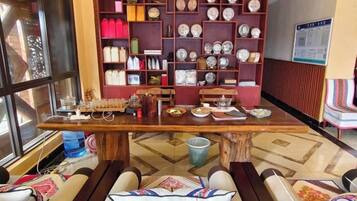 Una habitación con una mesa de madera, repisas con adornos y asientos con cojines.